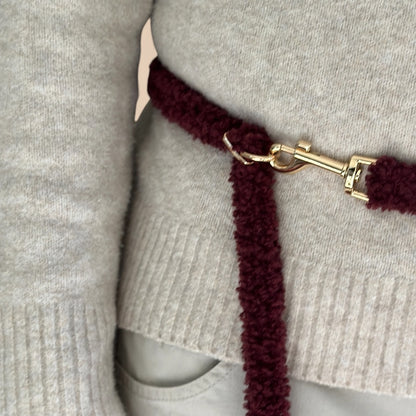 a dark burgundy fuzzy teddy dog leash  with a gold-tone clasp. The teddy multifunctional leash has white text reading TRUFOIS.